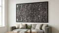 Puede incluir: Una gran obra de arte mural floral en blanco y negro con un diseño detallado y en capas. La obra de arte es rectangular y está enmarcada, montada sobre un sofá gris en un salón. El intrincado patrón se asemeja a una flor estilizada.