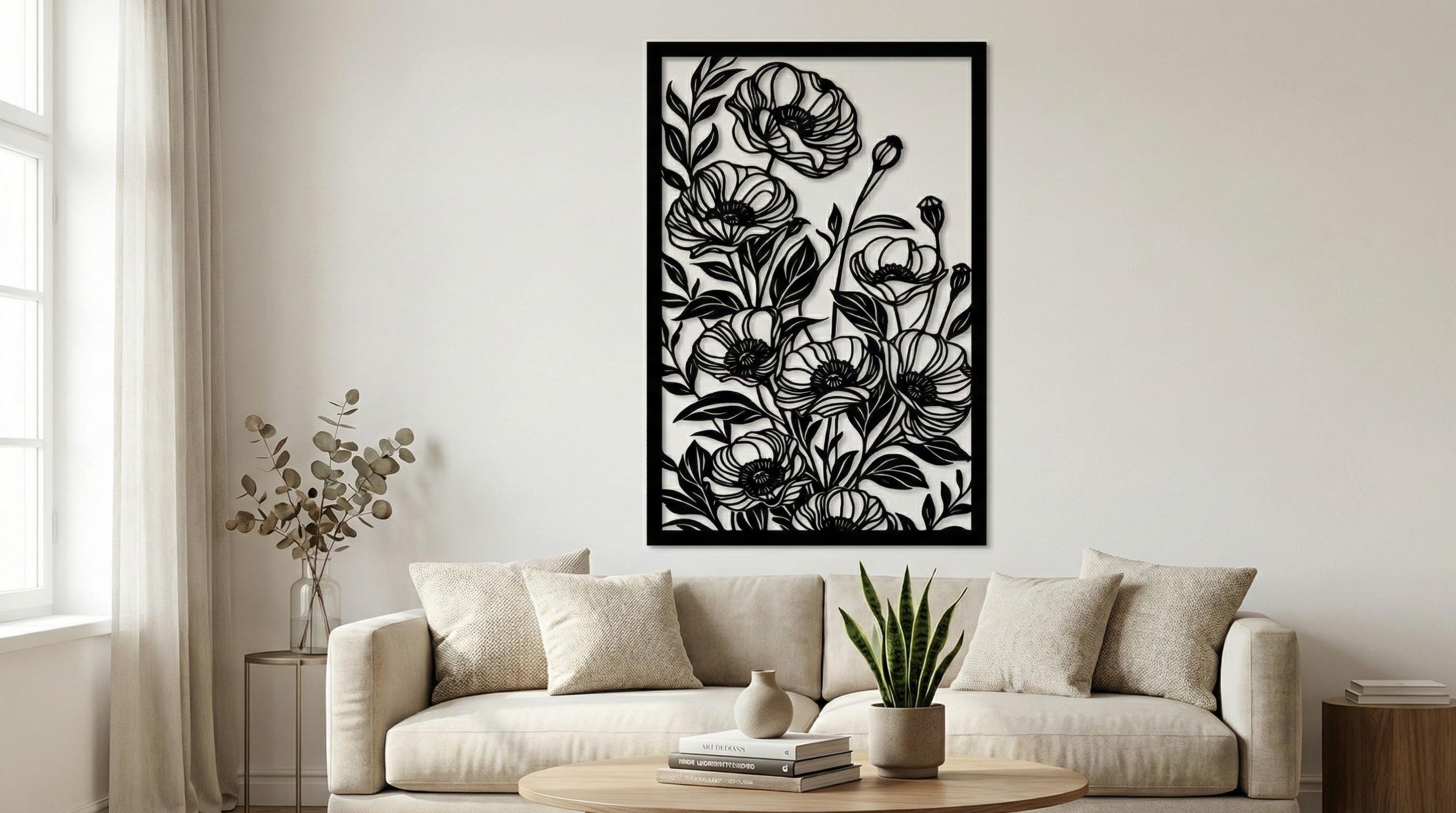 Puede incluir: Arte mural floral negro con un diseño recortado detallado de amapolas y hojas. La obra de arte está enmarcada en un borde rectangular negro. La pieza se exhibe sobre un sofá beige, agregando un toque de decoración inspirada en la naturaleza.
