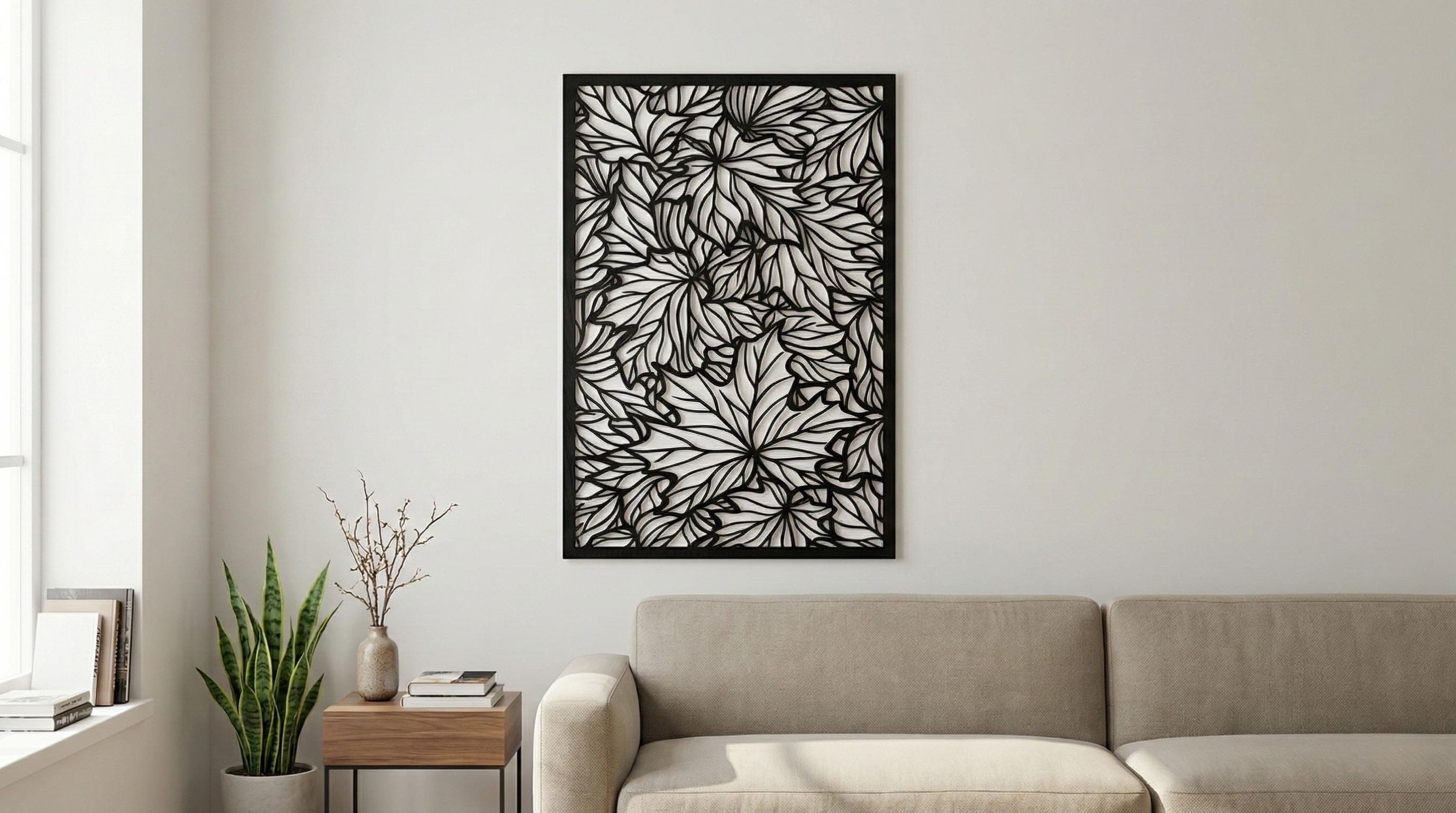 Puede incluir: Una obra de arte mural en blanco y negro con un patrón repetido de hojas de arce. Las hojas están intrincadamente recortadas, creando un diseño de espacio negativo. La obra de arte es rectangular y está enmarcada en negro, montada en una pared blanca.