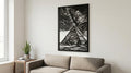 Puede incluir: Arte mural en blanco y negro que representa una escena de pirámides con un cielo nublado. La obra de arte tiene forma rectangular y está montada en una pared blanca sobre un sofá beige. Una planta en maceta y libros están sobre una mesa auxiliar de madera.